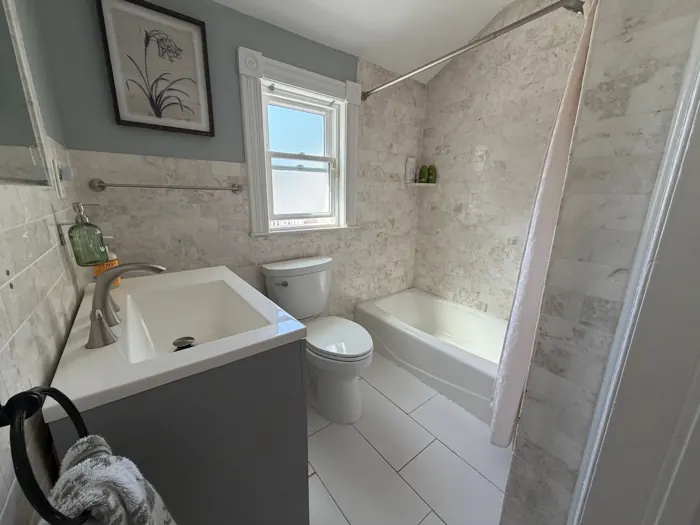 First-floor bathroom with marble-look tile and new vanity